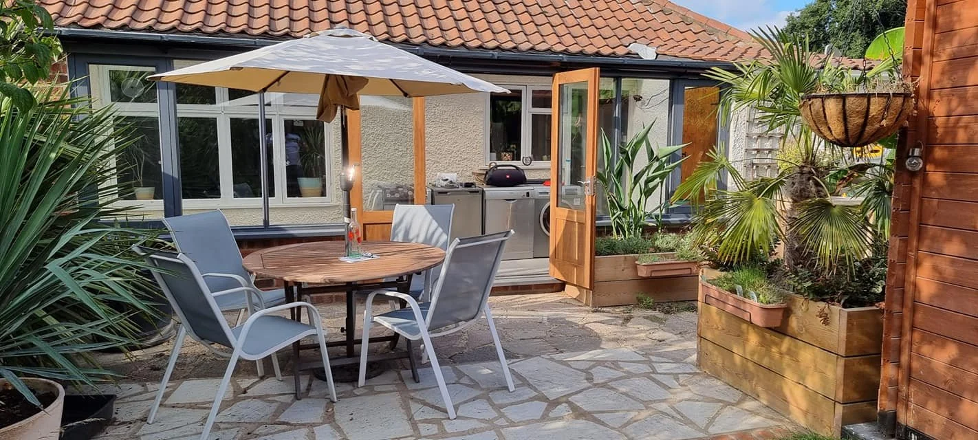 Glazed timber garden room opening onto a furnished terrace